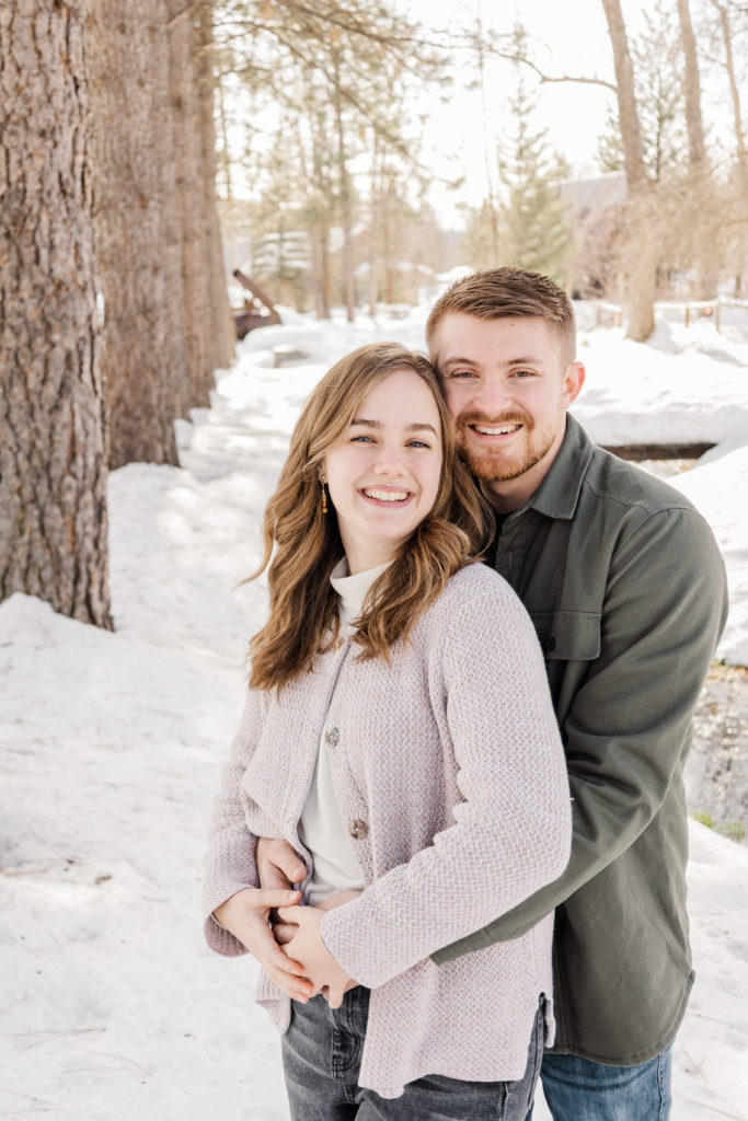 Couples posing with guy holding girl for couples photography in snowy forest.