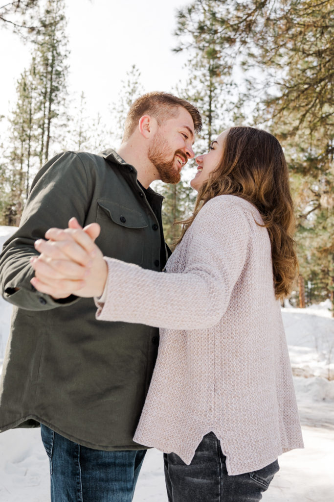 Couple posing in forest holding hands for winter couples photography.