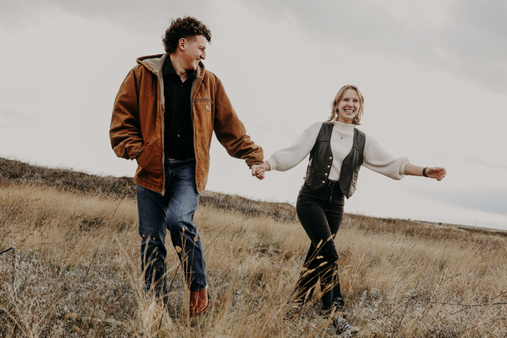 Couples photography with guy leading girl through feild. 